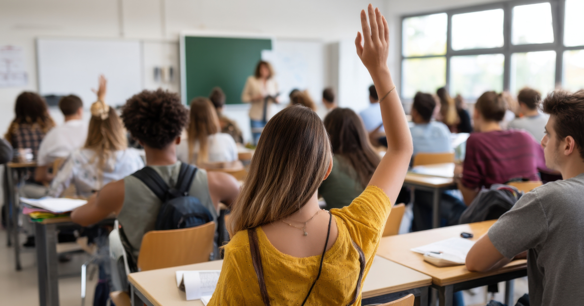 Student with hand raised in full classroom